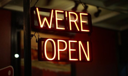 Photo of neon sign displaying the words: "We're Open"