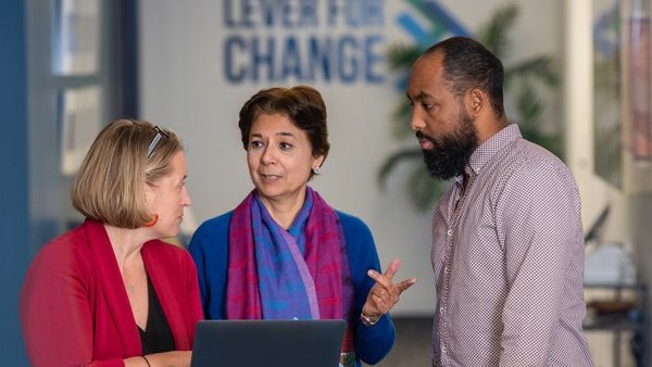 Lever for Change colleagues discuss work in an office hallway